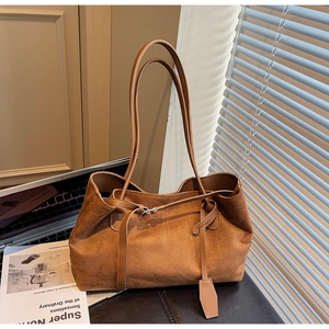 Detailed texture of dark brown suede shoulder bag featuring minimalist tie knot design