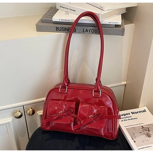 Détail du sac Boston en cuir verni rouge avec nœuds décoratifs et zips argentés