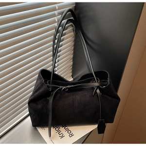 Close-up of black suede tote bag with slim shoulder straps in natural sunlight shadow