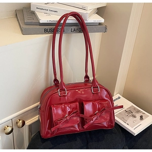 Détail du sac à main en cuir verni rouge avec nœuds et deux poches frontales