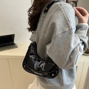 Fashionable black patent leather crescent bag with silver chain strap and metal rivets