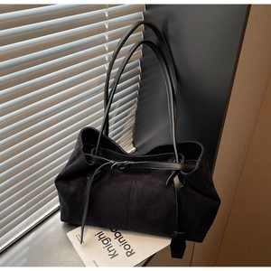 Detail of minimalist black faux suede tote bag with slim shoulder straps and matte finish