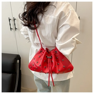 Detailed view of a red drawstring bucket bag with silver studs worn by a model