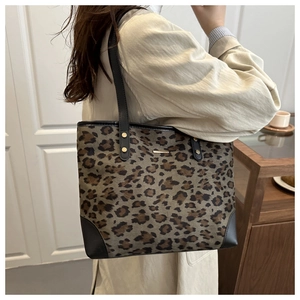 Detail of leopard print tote bag with black leather trim and golden metal rivets