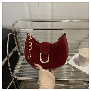 Dettaglio di una borsa a sella bordeaux in pelle scamosciata con fibbia a D dorata