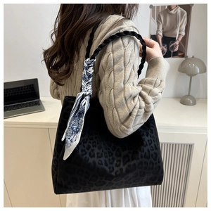 Detail of black leopard print tote bag with woven shoulder strap and silk scarf decor