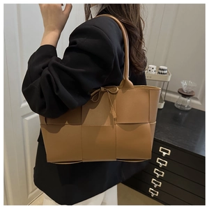 Brown woven leather tote bag with bow detail shown on shoulder for daily commute