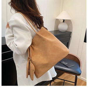 Detail view of large camel suede tote bag with matching mini purse on shoulder