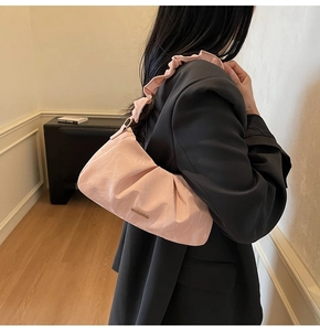 Dettaglio della borsa nuvola rosa con logo in metallo e tracolla a pieghe sulla spalla
