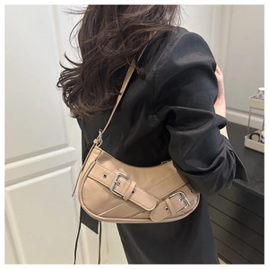 Detail view of retro beige underarm bag with silver buckles worn by a model
