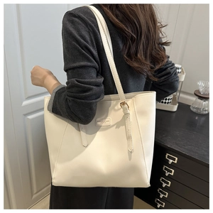 Detail of off-white PU leather tote bag with metal nameplate and adjustable shoulder strap