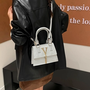 Silver sequin crossbody bag with gold V-logo and tassel detail on female model