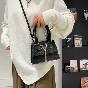 Elegant black leather crossbody bag with sequin detail and gold tassel metal logo