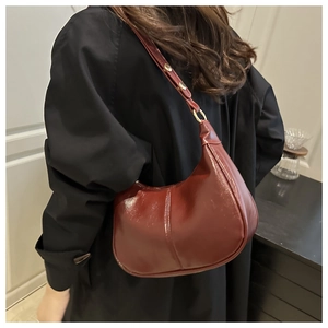 Close-up of wine red crescent bag featuring glossy leather texture and gold hardware details