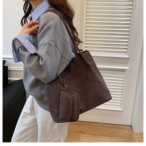 Detail of dark brown faux suede tote bag with matching zipper pouch on model's shoulder