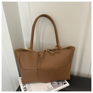 Detail of caramel brown woven leather tote bag with a small decorative front bow knot
