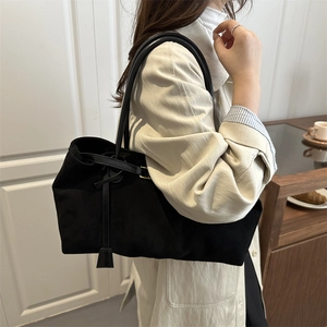 Retro black suede tote bag with long straps shown on shoulder for a minimalist look