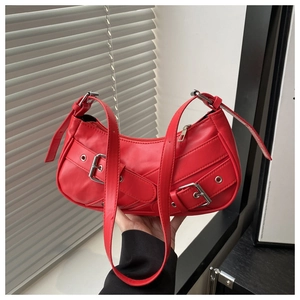 Detail of red PU leather baguette bag featuring silver buckles and metallic eyelets