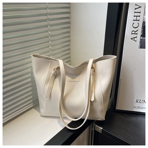 Detail of cream white tote bag with adjustable straps and fashion label on window sill