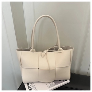 Close-up of cream woven faux leather tote bag with wide cross-braided design and top ties