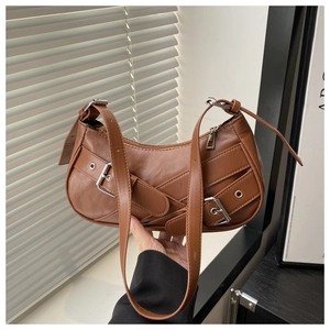 Macro detail of brown faux leather moon bag showing silver metal eyelets and straps