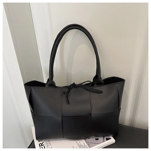 Detailed view of black woven large tote bag with top tie closure and long shoulder straps