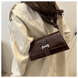 Détail du sac porté épaule en cuir marron foncé avec boucle H et bandoulière à nœud élégant