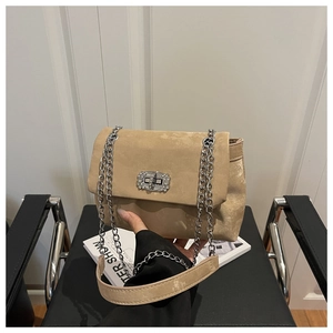 Close-up of beige suede shoulder bag featuring a sparkling rhinestone turn-lock and chain