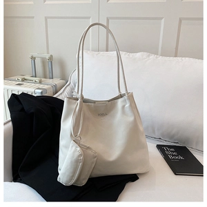 Minimalist white tote bag set with small pouch on sofa, chic faux leather lifestyle shot