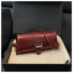 Close-up of a burgundy patent leather handbag with a silver metal clasp in a gift box
