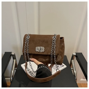 Detailed shot of brown frosted suede crossbody bag with silver chain and crystal lock