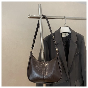 Detail of dark brown glossy leather hobo bag with adjustable metal buckle on strap