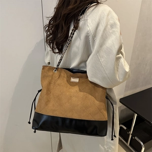 Quilted tote bag with suede finish and metal chain strap shown on a model in trench coat