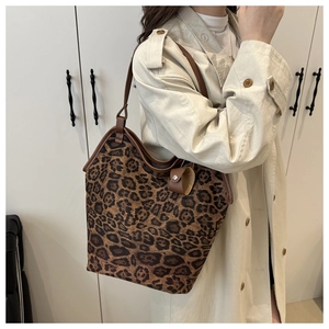 Dettaglio macro della borsa tote leopardata con cinturino in pelle marrone e charm