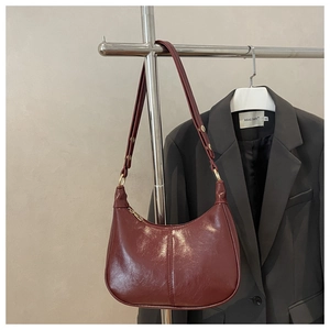 Detail view of burgundy crescent dumpling bag in glossy faux leather with gold hardware