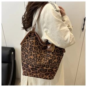 Dettaglio della borsa tote leopardata con manici in pelle marrone indossata da modella