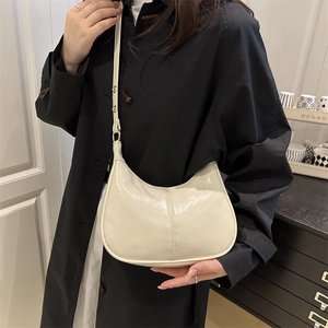 Minimalist cream crescent shoulder bag in glossy leather with adjustable strap