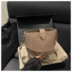 Detail of light brown bucket bag with lychee texture leather and gold heart buckle