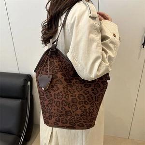 Elegante borsa a secchiello leopardata con tracolla in pelle in un ambiente d'interni