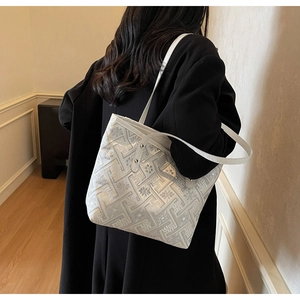 Detail of white tote bag with embossed geometric patterns and silver rivet studs