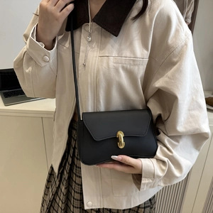 Borsa a tracolla minimalista in pelle nera da donna con chiusura dorata su modella