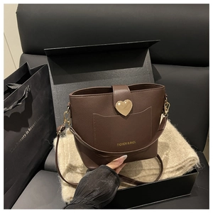 Detail of coffee bucket bag with litchi texture and golden heart buckle in a gift box