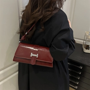 Sac baguette bordeaux minimaliste avec boucle en H argentée porté par un mannequin