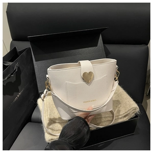 Detail of white bucket bag featuring pebble leather and heart-shaped gold buckle