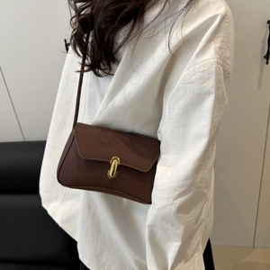 Elegante borsa a tracolla in pelle marrone scuro con fibbia dorata indossata su camicia