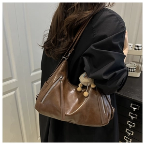 Detail of dark brown matte leather tote bag with zip pockets and a plush sheep charm