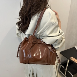 Glossy caramel brown shoulder bag with bow drawstring detail and long straps for women