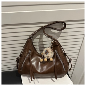 Detail of dark brown leather tote bag with silver zippers and plush charm decoration