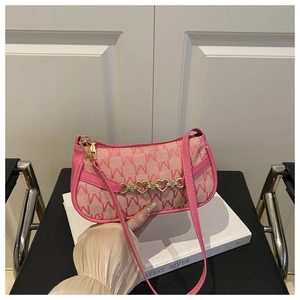 Dettaglio borsa a spalla rosa con motivo jacquard e catena dorata a forma di cuore