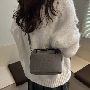 Sac bandoulière chic gris foncé imprimé léopard avec fermoir doré porté par mannequin